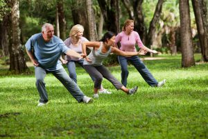 Multi-ethnic group of adults practicing tai chi in park. Main focus on Asian woman.