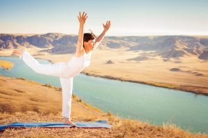 Inspired asian woman doing exercise of yoga at mountain range of Kazakhstan. She dressed in white sportswear.